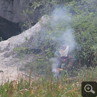 A native fisherwoman warms herself in winter by a fire.